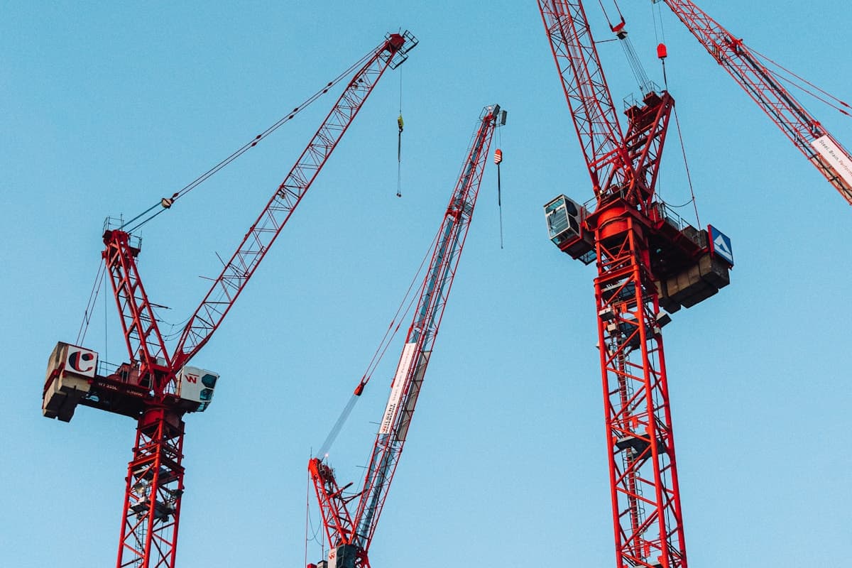 A mobile crane lifting a steel beam into position on a construction site in the UAE