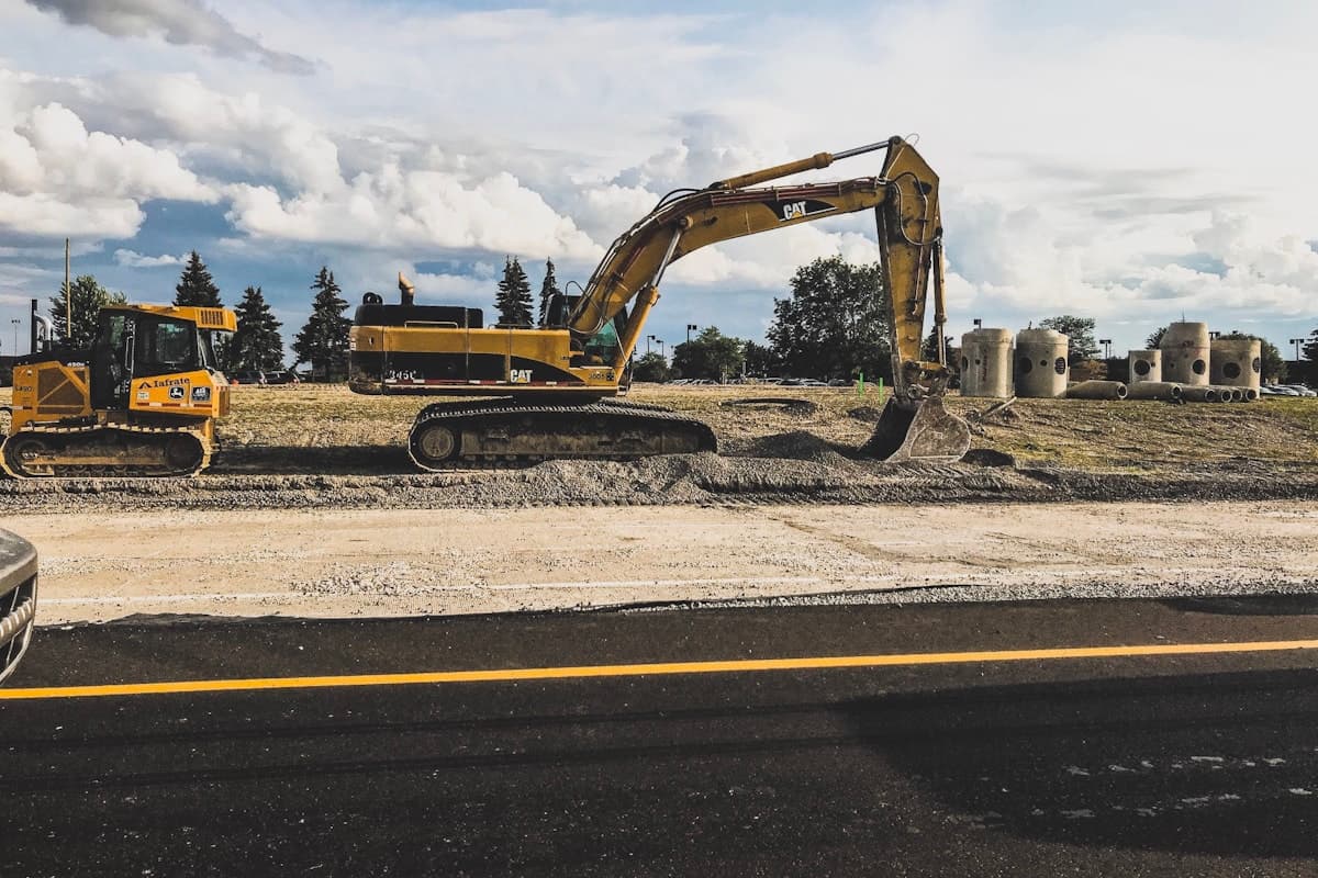 An excavator being offloaded from a lowbed trailer at a construction site entrance