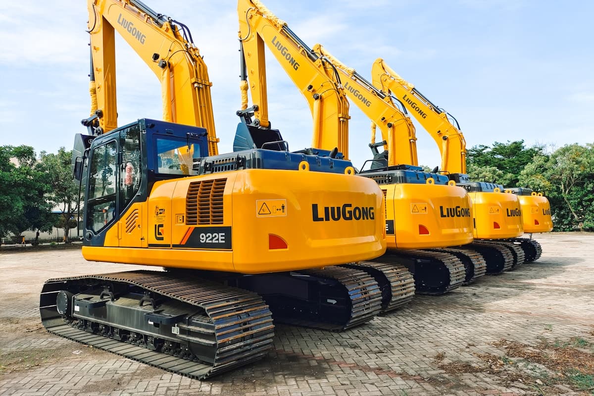 Mixed heavy equipment including forklifts, an excavator and a mobile crane staged in a rental yard