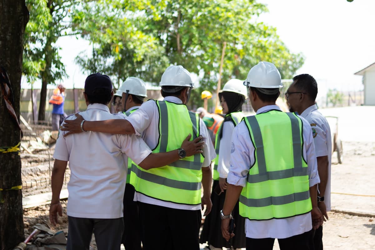 A site crew wearing high-visibility gear gathered around a mobile crane for a pre-lift safety briefing